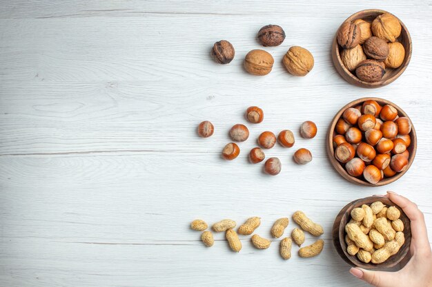 Vista superior de avellanas frescas con maní y nueces en mesa blanca