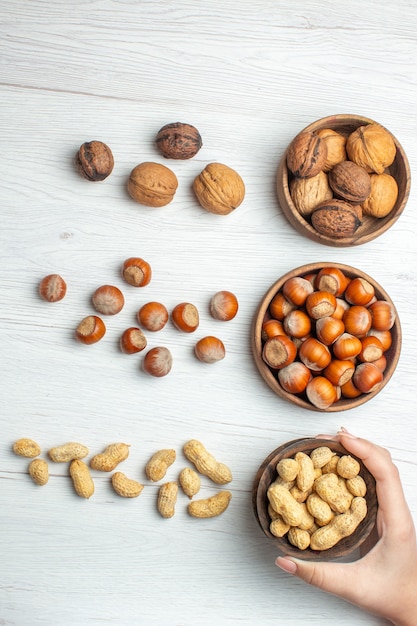 Vista superior de avellanas frescas con maní y nueces en mesa blanca