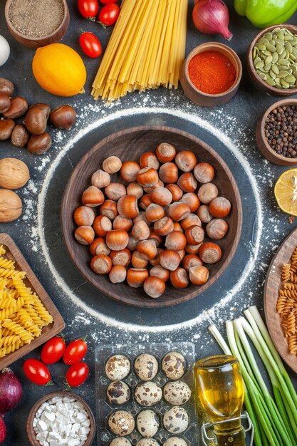 Vista superior de avellanas frescas con nueces, verduras, pasta y condimentos sobre un fondo oscuro, color, comida, foto, nuez, pimienta, comida