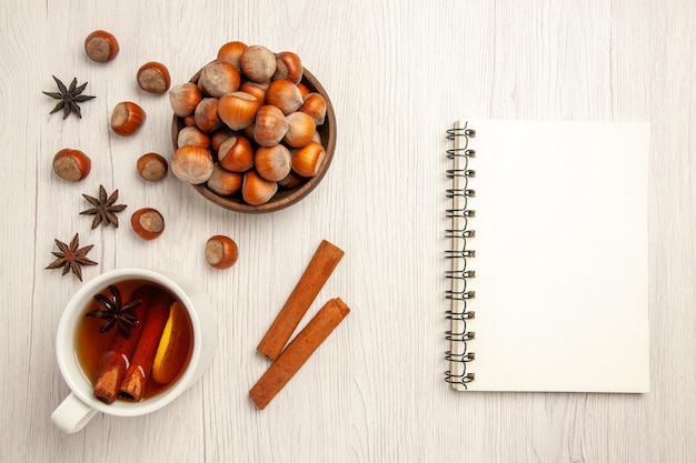 Vista superior de avellanas frescas con una taza de té en el escritorio blanco nuez bebida snack avellana nuez