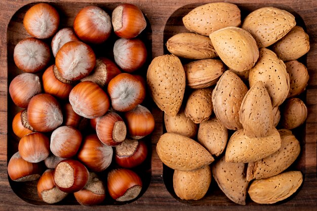 Vista superior de avellanas nueces con almendras con cáscara en una bandeja de madera