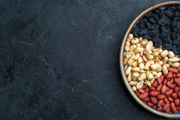 Vista superior de avellanas y pasas y otras nueces en un escritorio gris oscuro bocadillo de frutos secos