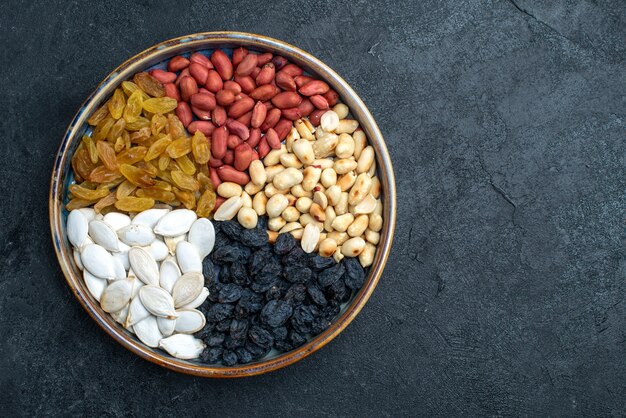 Vista superior de avellanas y pasas y otras nueces sobre fondo gris oscuro nueces bocadillos fruta seca