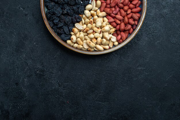 Vista superior de avellanas y pasas y otros frutos secos sobre fondo gris oscuro frutos secos snack de frutos secos