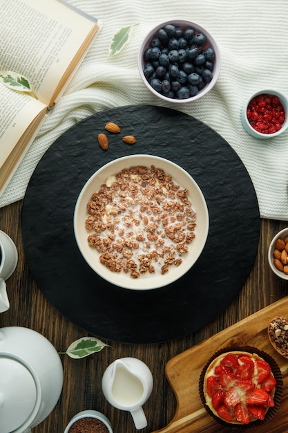 Vista superior de avena con leche de nuez y almendras en salvamanteles con endrino rojo grosella pastel de fresa leche libro abierto sobre tela sobre fondo de madera