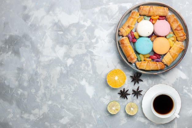 Vista superior de bagels dulces con macarons y taza de té en blanco