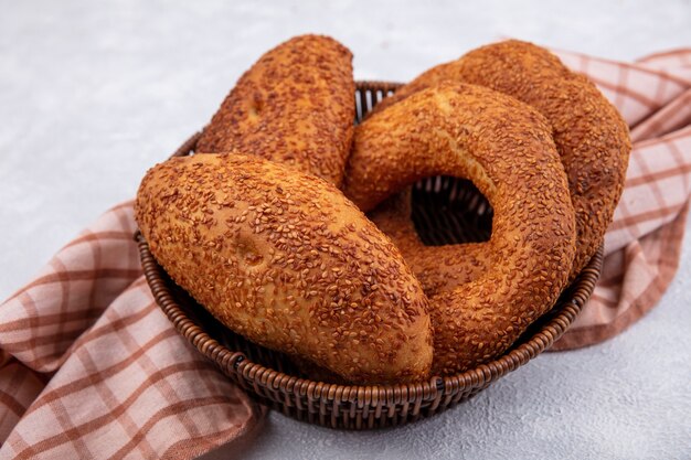 Vista superior de bagels turcos sabrosos y frescos con empanadas en un cubo sobre un paño a cuadros sobre un fondo blanco.