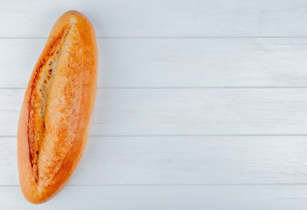 Vista superior de baguette francés sobre fondo de madera con espacio de copia