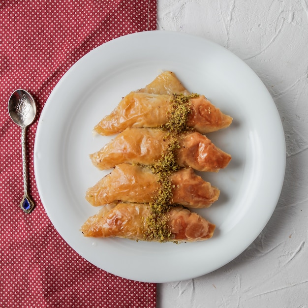 Foto gratuita vista superior baklava turco con trapo y cuchara en plato redondo