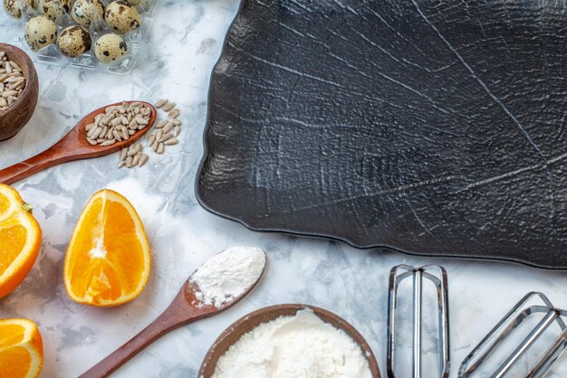 Vista superior de la bandeja negra cuchara de madera huevos naranjas frescas sobre fondo de hielo