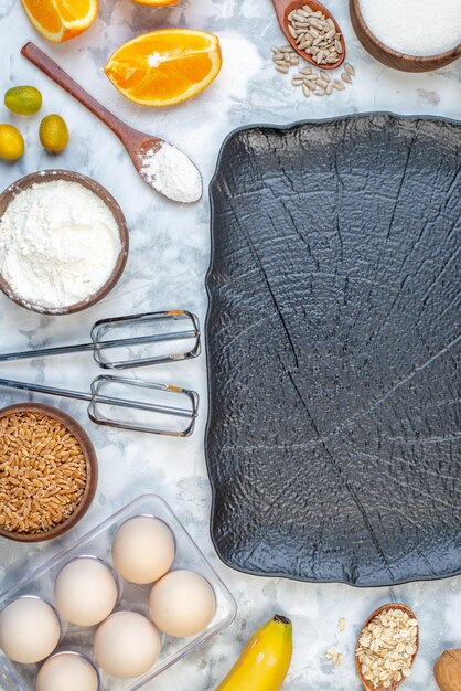 Vista superior de la bandeja negra y la cuchara de naranjas frescas arroz integral en una olla huevos sobre fondo de hielo