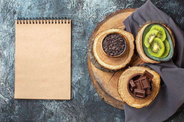 Vista superior de barras de chocolate con kiwis en rodajas sobre fondo gris oscuro pastel color dulce desayuno azúcar postre