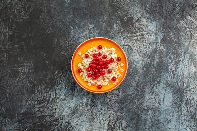 Vista superior de las bayas las apetitosas grosellas rojas en la placa naranja sobre la mesa gris