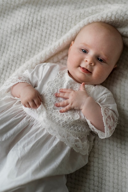Vista superior bebé sonriente en vestido blanco