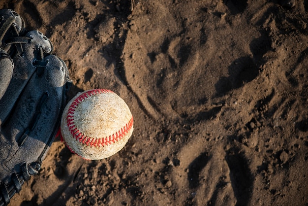 Vista superior de béisbol y guante sobre tierra