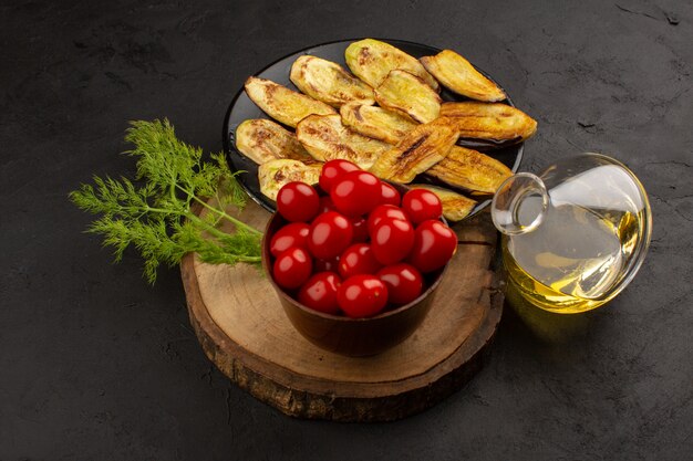 vista superior berenjenas cocidas junto con tomates rojos y aceite de oliva en el piso oscuro