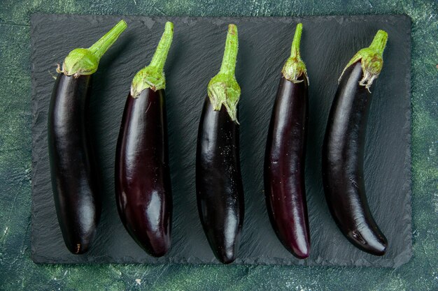 Vista superior berenjenas negras sobre la superficie oscura alimentos color fresco ensalada madura comida vegetal