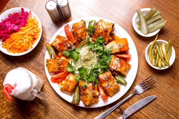 Vista superior de beyti kebab servido con ayran y pepinillos
