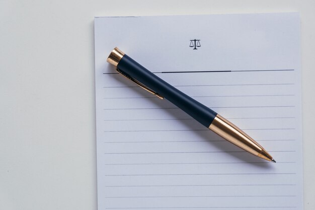 Vista superior de un bolígrafo colocado sobre un trozo de papel rayado blanco