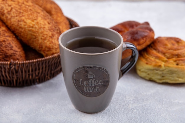 Vista superior de bollos frescos en un balde con una taza de té sobre un fondo blanco.