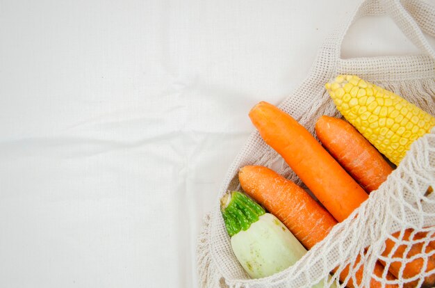 Vista superior bolsa con verduras sobre fondo blanco.