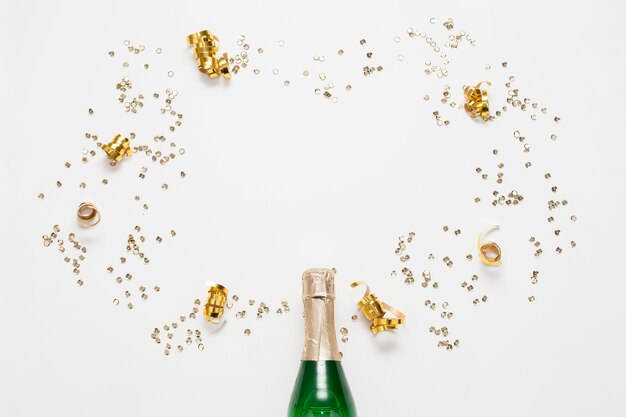 Vista superior botella de champagne con cintas doradas y confeti
