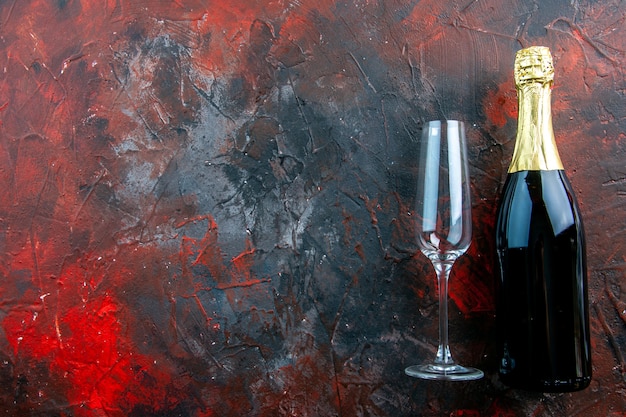 Vista superior de la botella de champán con copa en la bebida de fotografía de color de alcohol oscuro