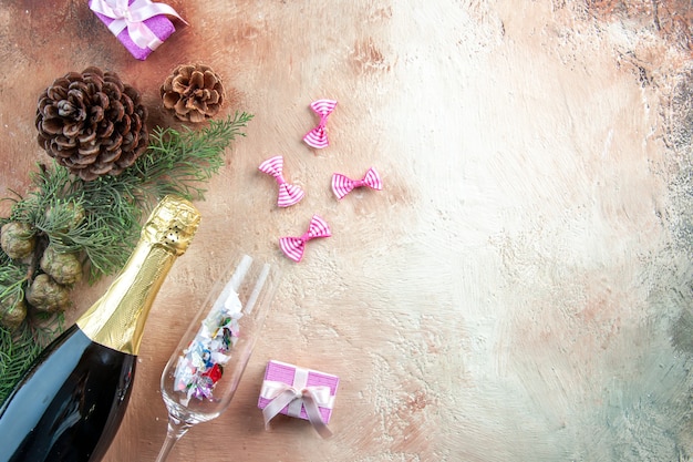Vista superior de la botella de champán con pequeños regalos en la luz de Navidad foto regalo de año nuevo en color espacio libre de alcohol