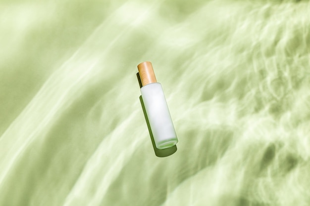 Foto gratuita vista superior de una botella de cuidado de la piel sobre una superficie con textura verde