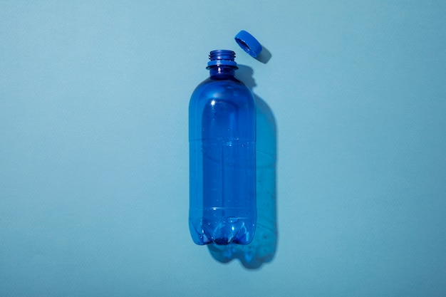 Vista superior de la botella de plástico sobre fondo azul.