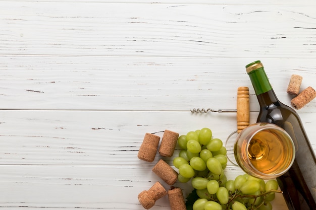 Vista superior botella de vino con vaso y racimo de uvas 