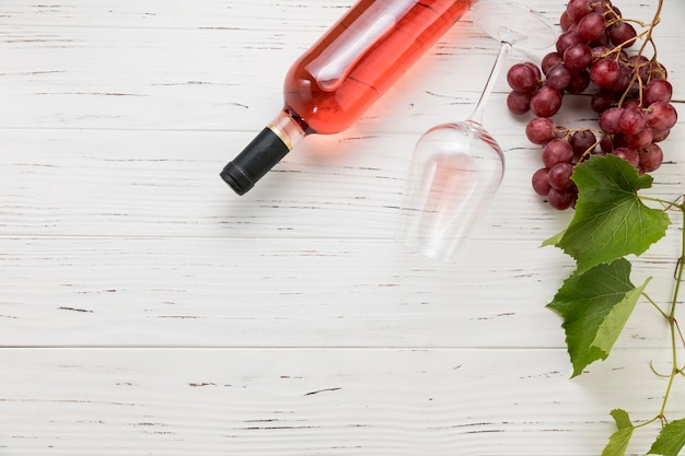 Vista superior botella de vino con vaso y racimo de uvas 