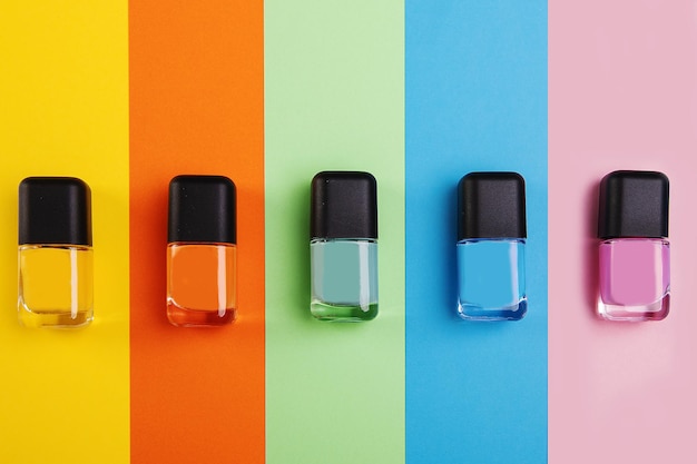 Vista superior de botellas de esmalte de uñas en diferentes tonos sobre una superficie colorida