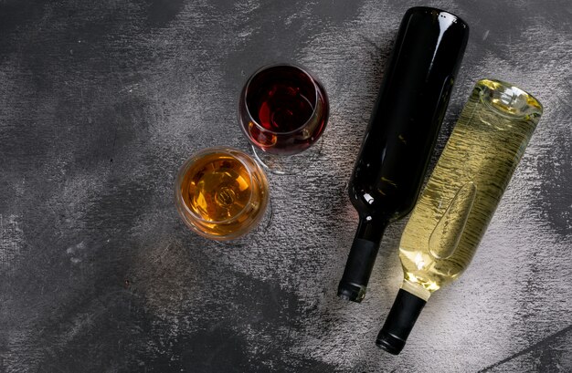 Vista superior de botellas de vino con copas y copia espacio en piedra negra horizontal