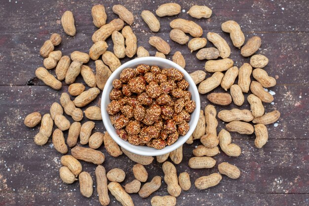 Vista superior de cacahuetes frescos con caramelos de nueces dulces y pegajosos en el fondo gris nueces dulces goody sal dulce