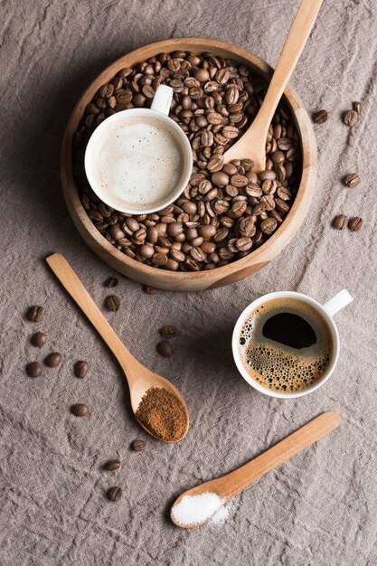 Vista superior de café y café con leche en tazas blancas con frijoles tostados