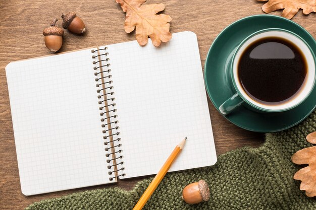 Vista superior de café con cuaderno y hojas de otoño