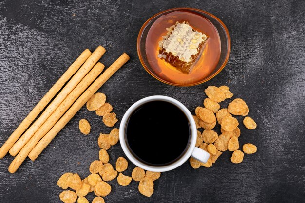 Vista superior de café con galletas y miel en superficie negra horizontal