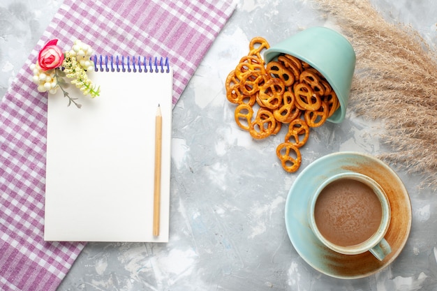 Vista superior de café con leche con bloc de notas y galletas en el escritorio ligero, bebe una fotografía en color nítido