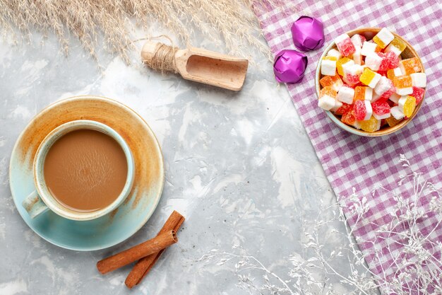 Vista superior de café con leche con canela y caramelos en el escritorio de luz dulces golosinas azúcar dulce