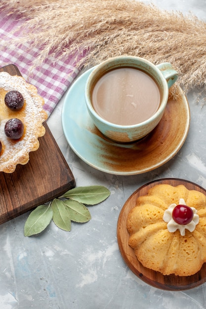 Vista superior de café con leche con tortas en mesa blanca pastel galleta azúcar dulce