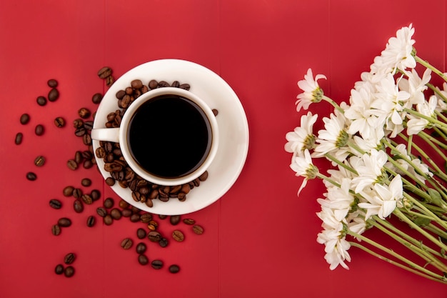 Vista superior de café en una taza blanca con granos de café sobre un fondo de res