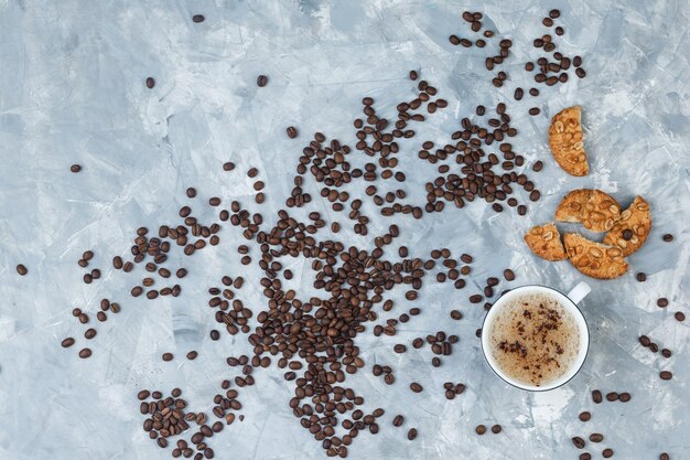 Vista superior de café en taza con galletas, granos de café sobre fondo gris sucio. horizontal