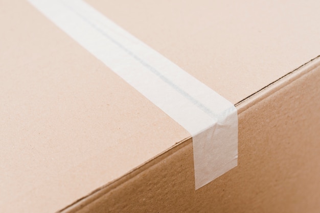 Vista superior de una caja de cartón sellada con cinta de embalaje blanca.