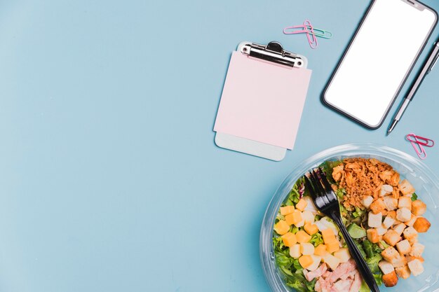 Vista superior caja de ensalada de trabajo con teléfono en blanco y espacio de copia