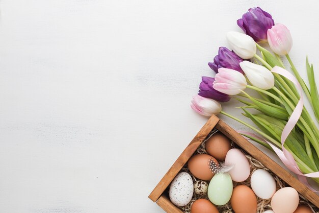 Foto gratuita vista superior de la caja con huevos para pascua y tulipanes multicolores