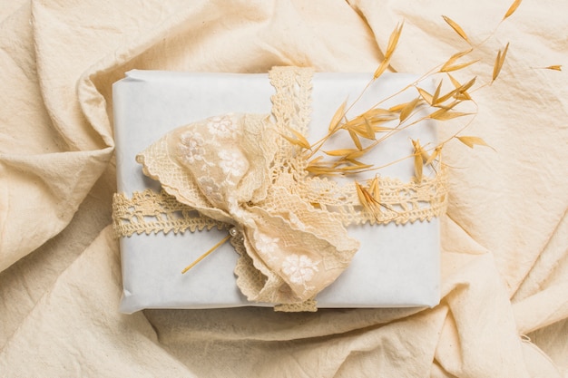 Vista superior de caja de regalo decorada sobre textil arrugada.