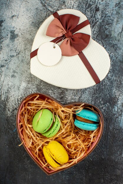 Vista superior de la caja de regalo en forma de corazón con deliciosos macarons sobre fondo helado oscuro