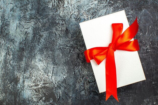 Vista superior de cajas de regalo bellamente empaquetadas atadas con cinta roja en el lado izquierdo en la oscuridad