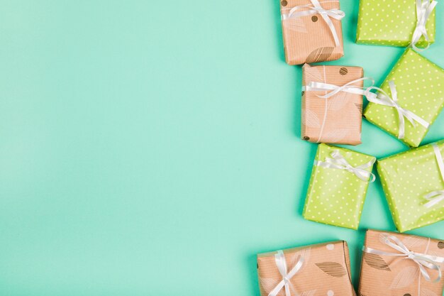 Vista superior de cajas de regalo envueltas en papel marrón y verde sobre fondo verde